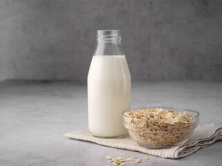 Vegan oat milk. Non-dairy alternative milk in a glass, oatmeal on a gray background, table. Ingredients for porridge Hercules. Copy space. Close up. Organic vegan non dairy milk. Concept of healthy.
