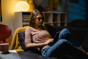 Obraz premium woman is using digital tablet while sitting on sofa at home