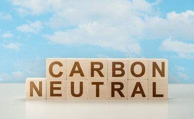 carbon neutral. text on wooden cubes neutral carbon laid out on white table against a blue sky with...