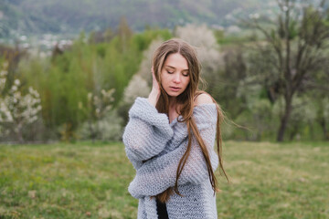 Obraz premium Young pretty emotional caucasian woman with long hair wearing natural makeup in romantic casual clothes walking among spring mountains near the beautiful fresh blooming tree in the countryside.