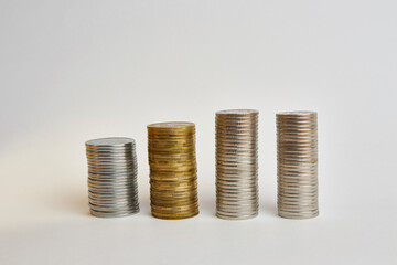 Four towers with coins of different denominations on a white background.