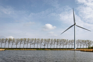 Middelharnis, The Netherlands, March 30, 2022: view across a lake towards a dike with a wind...