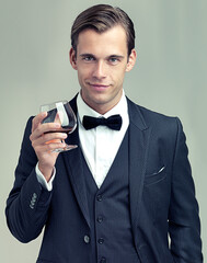 Heres to frivolity. A portrait of a dapper young man with a glass of wine wearing a vintage suit. - obrazy, fototapety, plakaty