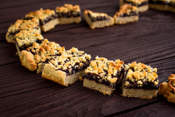 Shortbread cookies with currants laid out in the shape of a heart on a wooden brown table. Side view