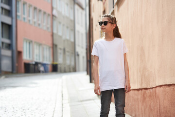 Obraz premium Child girl wearing white t-shirt with space for your logo or mock up outside in an urban area
