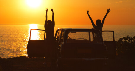 The sea brings out their inner little girls. Rearview shot of two unrecognizable girl friends cheering with their arms raised while on a road trip at the beach.