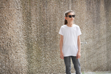 Child girl wearing white t-shirt with space for your logo or mock up outside in an urban area