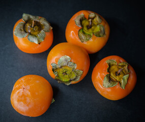 Persimmon fruits on dark background.
