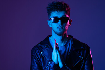 Neon light studio portrait of serious man model with mustaches and beard in sunglasses