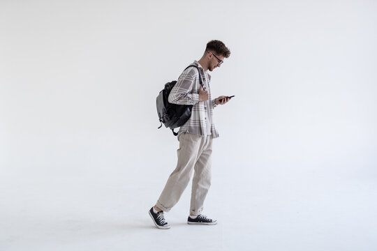 Side view portrait of a student walking with bag and mobile phone