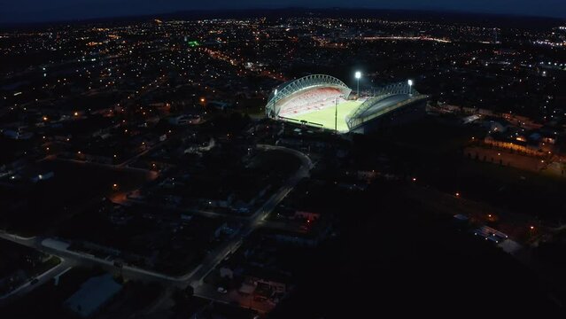 Descending panoramic footage of night city with glowing illuminated football stadium. Limerick, Ireland