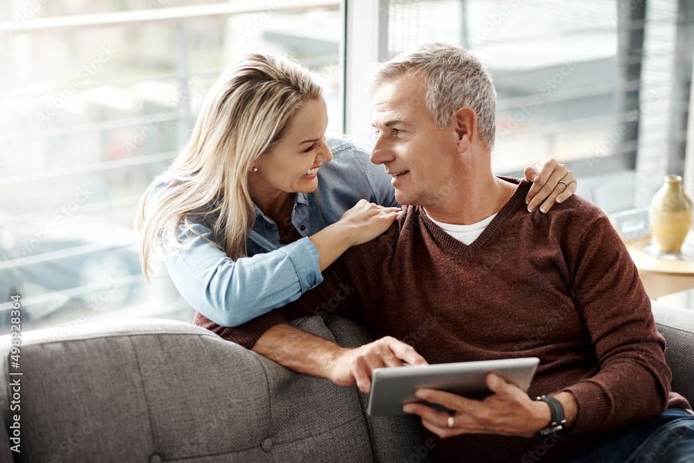 Poster theyve got an undeniable connection. shot of a mature couple using a digital tablet while relaxing t