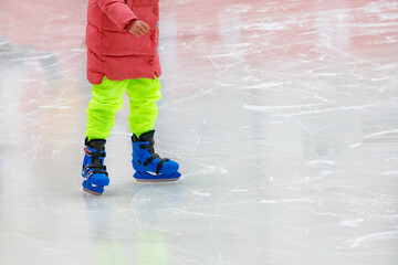 A teenager in bright clothes is skating in an ice stadium.