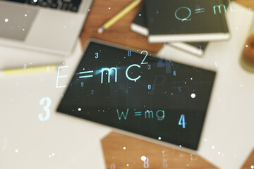 Double exposure of creative scientific formula concept and digital tablet on background, top view,...