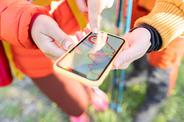 Couple of hikers looking at a map and smartphone at the edge of the forest road, snow-capped Sierra...