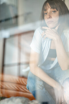 Portrait of a young confident woman sitting on couch at home. Double exposure image technic
