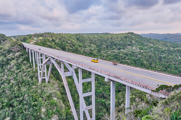 Fototapeta na wymiar The highest of Cuba Bacunayagua Bridge. Automobile and horse-drawn transport moving along bridge.