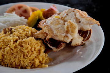 Baked lobster tail with yellow rice and vegetables.