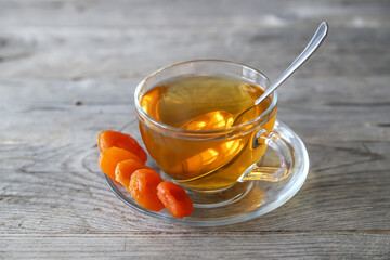 Tea in a glass cup and dried apricots on a saucer. Tea drinking with healthy dry fruits