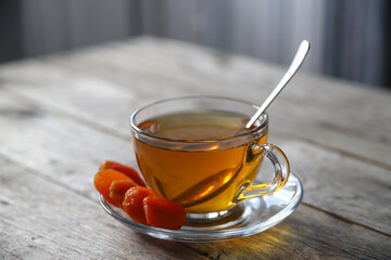 Tea in a glass cup and dried apricots on a saucer. Tea drinking with healthy dry fruits