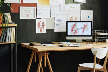 Empty workplace with computer monitor on it for online education with medicine poster on wall