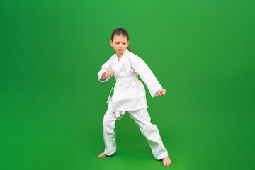 A karate girl does stretching before training in the gym. The child is engaged in martial arts.