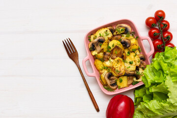 Baked gratin dauphine at home on a wooden table with cherry tomatoes.