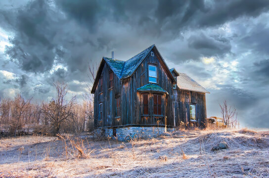 An old abandoned house in winter on a farm yard in rural Canada