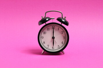 vintage old black alarm clock on pink background