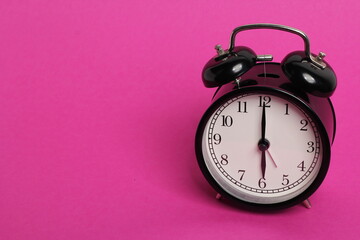 vintage old black alarm clock on pink background