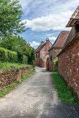 Fototapeta na wymiar Street with perfectly preserved medieval residential masonry buildings on outskirts of Collonges-la-Rouge. Correze department, New Aquitaine region, France