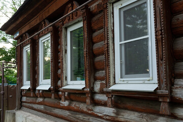 Fototapeta premium The beautiful old windows with beautifully designed platbands window on an old wooden house in the city of Tula