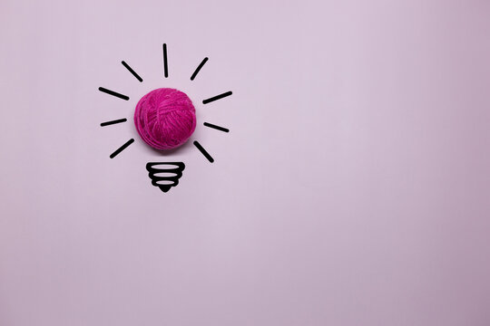 Creative thinking ideas and innovation concept. A ball of pink threads with a light bulb symbol on a violet background