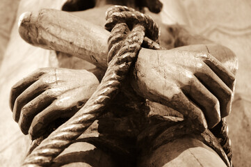 Wooden statue of Jesus with tied hands. Sepia photo. - obrazy, fototapety, plakaty