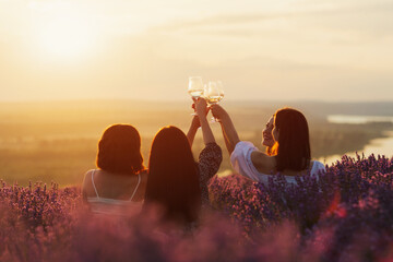 Friends having picnic in the lavender field. Group of young women sitting on lavender field at...