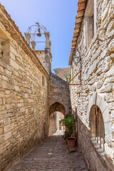 Fototapeta na wymiar Narrow cobblestone street, vernacular architecture, bell clock tower of Lacoste, Vaucluse, France