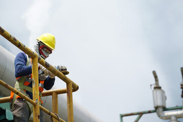 Male welder worker wearing protective clothing fixing welding and grinding industrial construction oil and gas or water plumbing pipeline outside on site