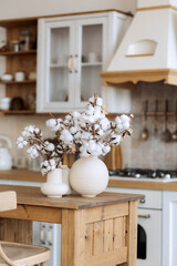 stylish kitchen in the old style, light, wooden, with stone tiles. Cotton in a vase. Composition in a ceramic pot.