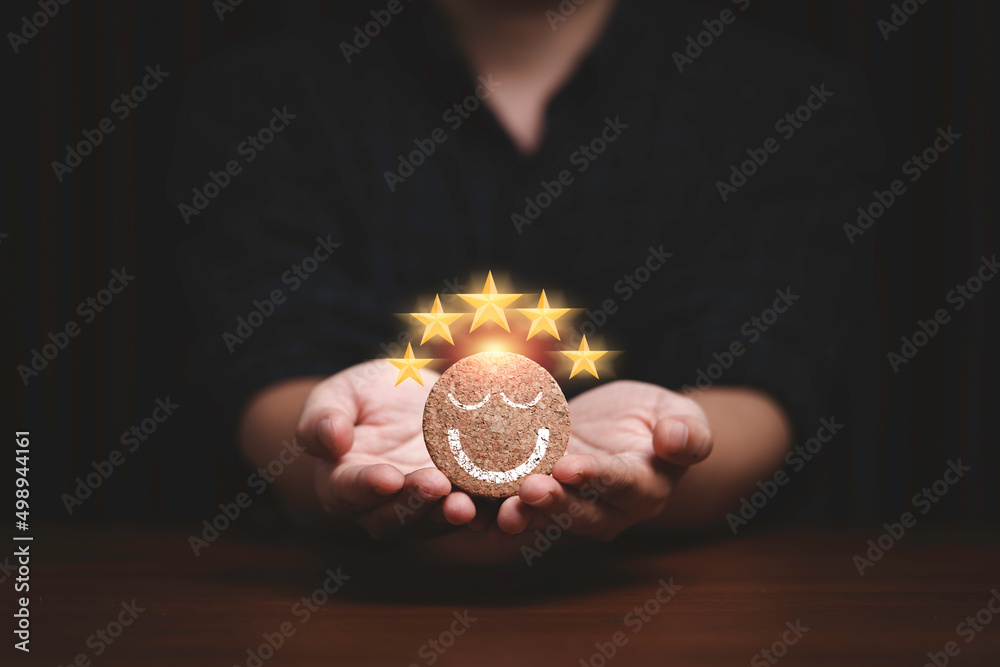 Poster businessman holding and giving smile face with five golden stars which print screen on round wooden 