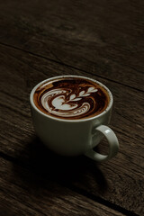 A cup of coffee mocha with tulip shape latte art on wooden table, top view