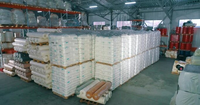 Spunbond in rolls in the warehouse of the factory. Warehouse of raw materials at the factory. Lots of raw material bag for production.