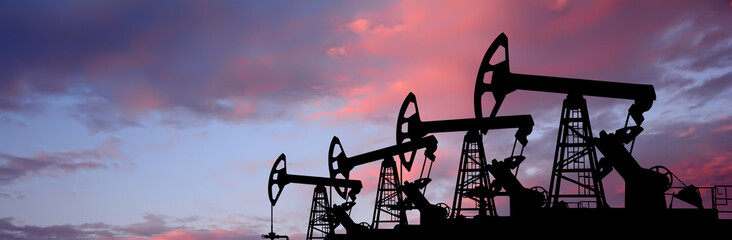 Pump- jacks on sunset background. Oil production
