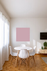 Table detail with white chairs and wooden legs. above the table is a pink frame