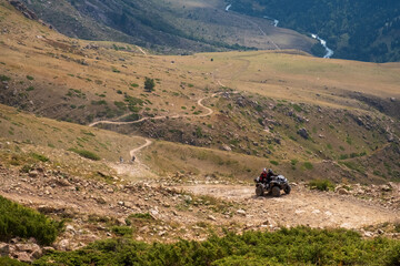 Mountain gravel road with ATV quadbike. Kapalskiy vzvoz mountain pass. Road to Burkhan-bulak waterfall. Travel, tourism in Kazakhstan.