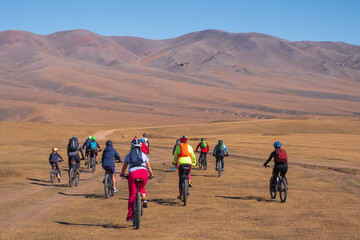 Group of cyclists are riding bikes on mountain plateau. Cycle tour on Assy plateau. Travel, tourism in Kazakhstan concept.