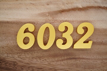 Golden Arabic numerals on a real brown and white wooden floor number 6032