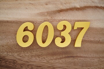 Golden Arabic numerals on a real brown and white wooden floor number 6037