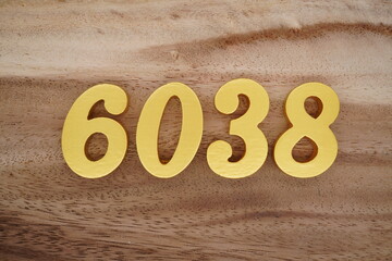 Golden Arabic numerals on a real brown and white wooden floor number 6038