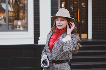 Stylish business woman in jacket and felt hat walks on the city street