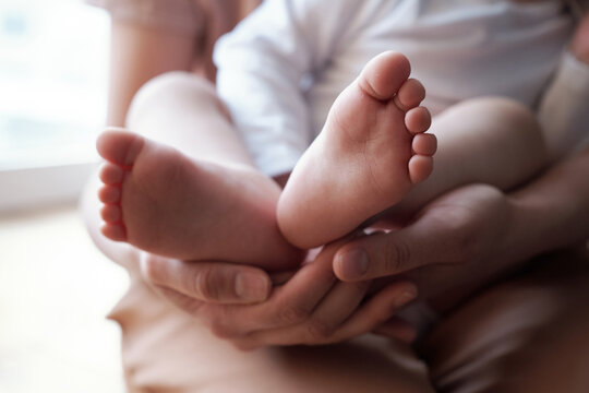 Close-up shot of cute small baby feet in loving mother hands, concept of happy family and motherhood